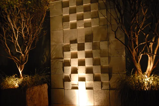 Parede de cubos iluminada de baixo entre árvores